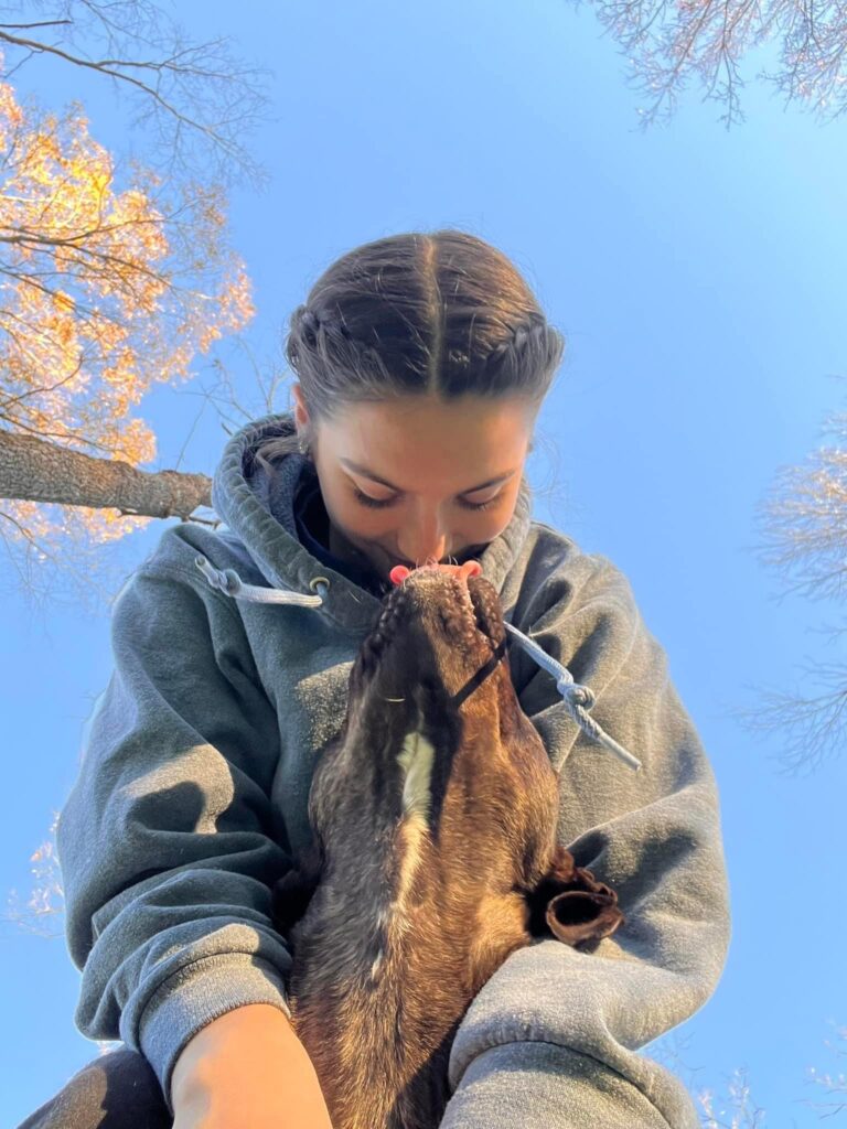 Woman looking down at a dog in her arms, dog is looking up to her and licking her.